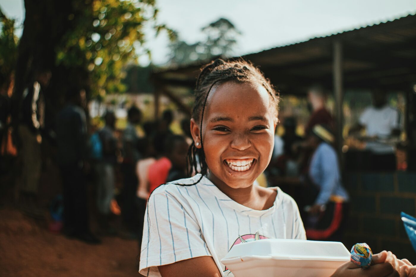 A smiling girl holding a meal at a community gathering