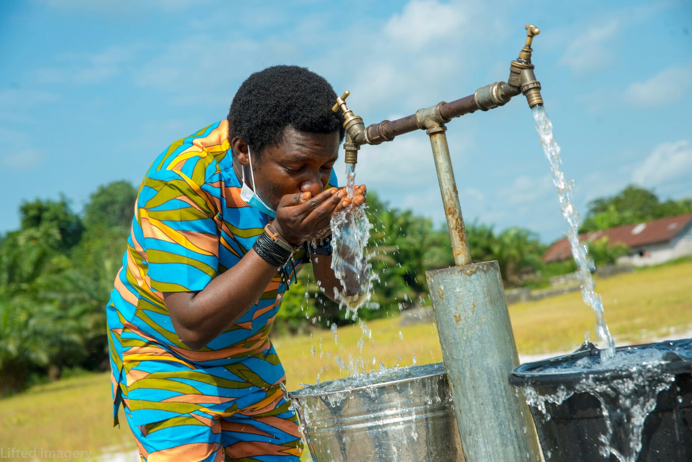 A community member drinking from a public water tap